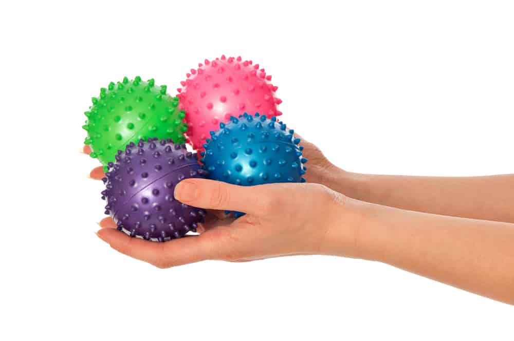 hands holding four spiky massage balls