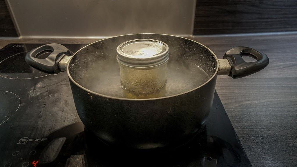 mason jar with chamomile oil in a pot of boiling water