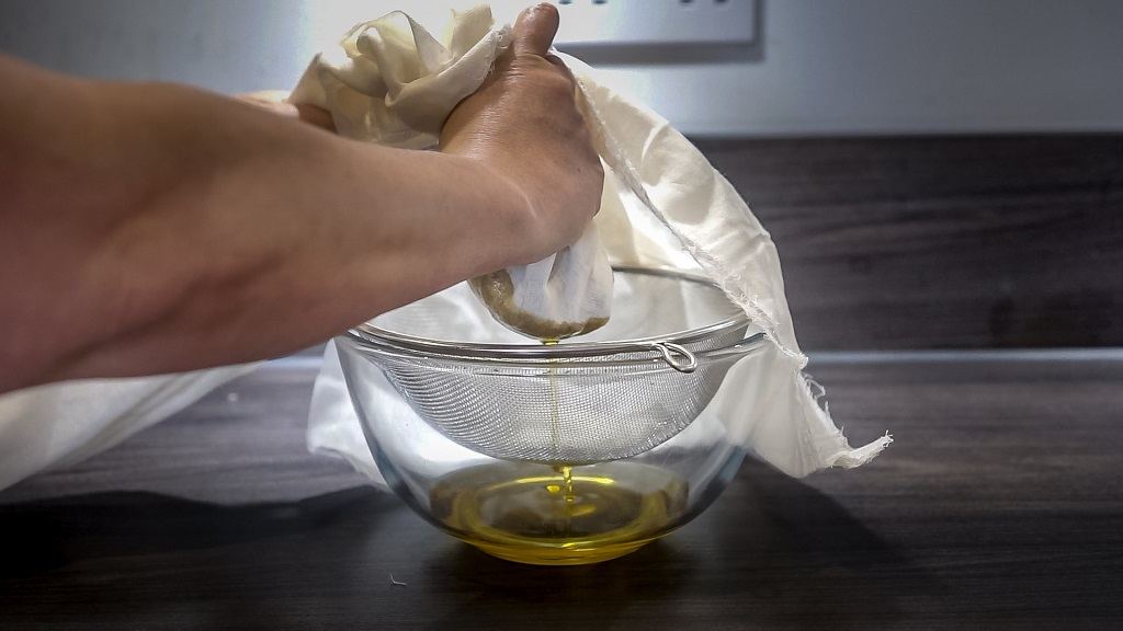 straining the chamomile face oil using a cheesecloth