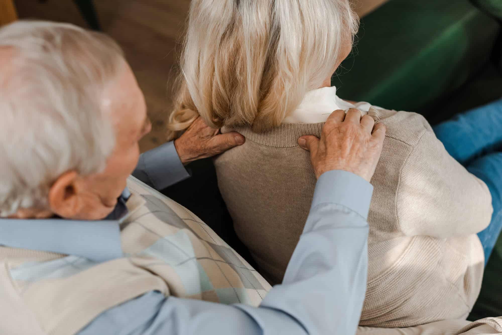 older man giving an older woman a shoulder massage at home